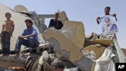 Libyans stand on the rubble of a home that was destroyed by a NATO bomb, allegedly killing two children and their mother in Zliten, in August 2011.