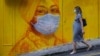 Беременная женщина на фоне мурала с изображением человека в маске.