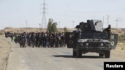 نیروهای امنیتی عراق در حال محافظت از شهروندانی هستند که خانه‌های خود را در پی درگیری‌ها میان نیروهای امنیتی و داعش رها کرده‌اند و به اماکن موقتی انتقال داده می‌شوند