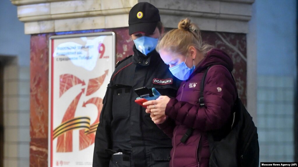 Москва, женщина показывает QR-код для поездки на транспорте полицейскому, 17 апреля 2020 года