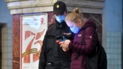 Женщина показывает полицейскому QR-код в своем смартфоне перед поездкой в метро. Москва, 17 апреля 2020 года.