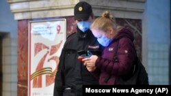 Метро алдында полиция қызметкеріне телефонындағы QR-кодты көрсетіп тұрған тұрғын. Мәскеу, 17 сәуір 2020 жыл.