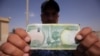 An Iraqi policeman holds a 10,000-Iraqi dinar note bearing an image of Mosul's leaning minaret, now destroyed.