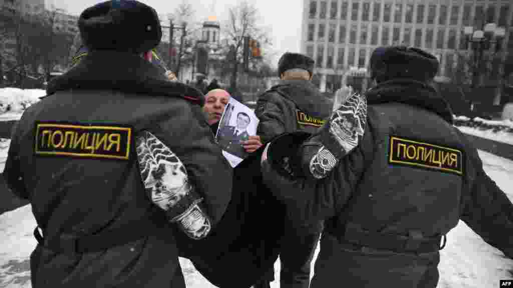 Russian Police officers detain an anticorruption protester holding a photo of Interior Minister Rashid Nurgaliyev, just outside the Interior Ministry headquarters in Moscow on January 18. (AFP/Andrey Smirnov) 
