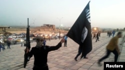 An Islamic State fighter holds an IS flag on a Mosul street. (file photo)