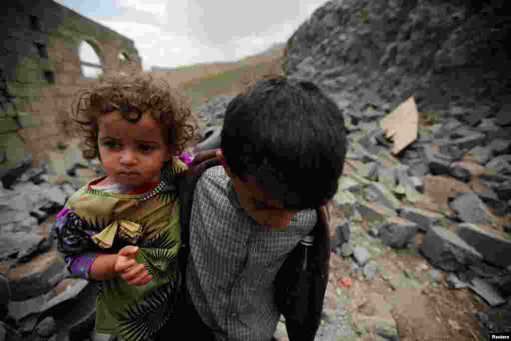 A boy carries his sister as he walks on the rubble of a house after it was destroyed by a Saudi-led air strike in Yemen's capital, Sanaa. (Reuters/Mohamed al-Sayaghi)