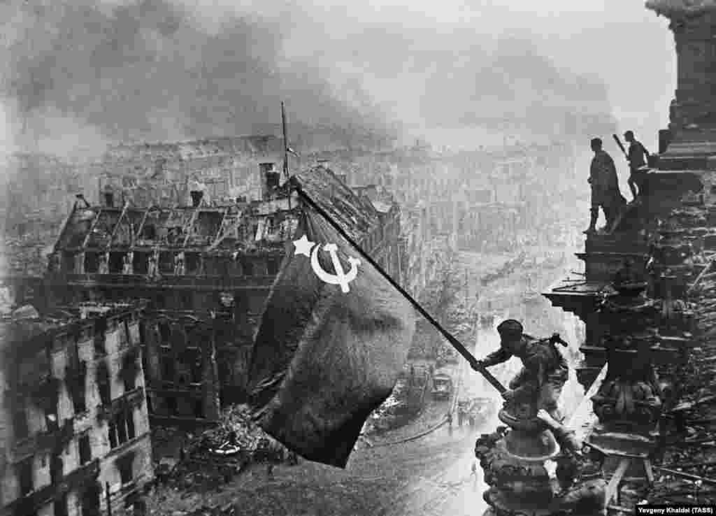 A Red Army soldier hoisting the Soviet flag above the Reichstag in Berlin on May 2, 1945. The photo would become both the defining image of the Red Army&#39;s victory over Nazi Germany and an example of the deception of Soviet propaganda.