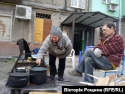 Місцеві мешканці Маріуполя готують їжу на польовій кухні біля свого будинку. Квітень 2022 року