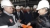 Prime Minister Vladimir Putin (right) dips his hand into a hardhat full of oil. Critics say he's likely delighted by international crises that have increased the value of Russia's chief export.