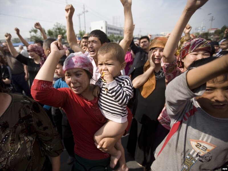 Уйгурская женщина с ребенком во время акции протеста уйгуров в Урумчи. 7 июля 2009 года.