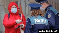 A woman shows identity papers to police officers enforcing a lockdown in Bucharest, which is about 360 kilometres from the northern city of Suceava.