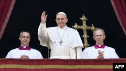 Pope Francis (center) waves from the balcony of St Peter's Basilica in the Vatican during the traditional "Urbi et Orbi" Christmas message to the city and the world on December 25.