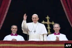 Pope Francis (center) waves from the balcony of St Peter's Basilica in the Vatican during the traditional "Urbi et Orbi" Christmas message to the city and the world on December 25.