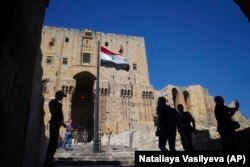 In a September 2017 photo, visitors and Russian military police officers walk toward the Citadel, Aleppo's famed fortress.