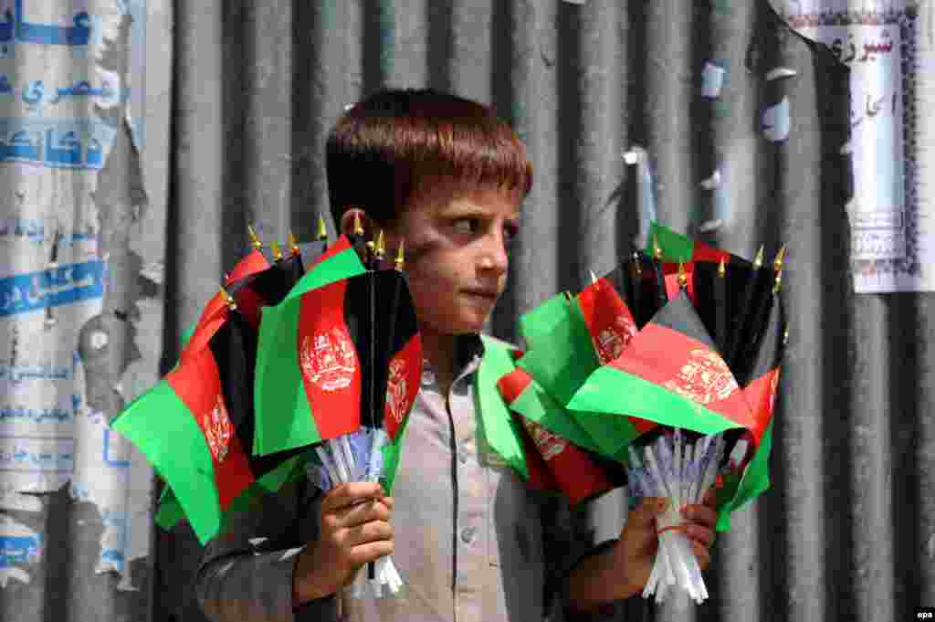 A young boy sells the Afghan national flag on a roadside ahead of the country's Independence Day (August 19) in Jalalabad on August 11. (epa/Ghulamullah Habibi)