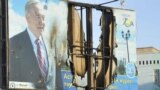 Жартылай жанып кеткен президент Нұрсұлтан Назарбаевтың бейнесі басылған банер. Жаңаөзен, 19 желтоқсан 2011 ж.