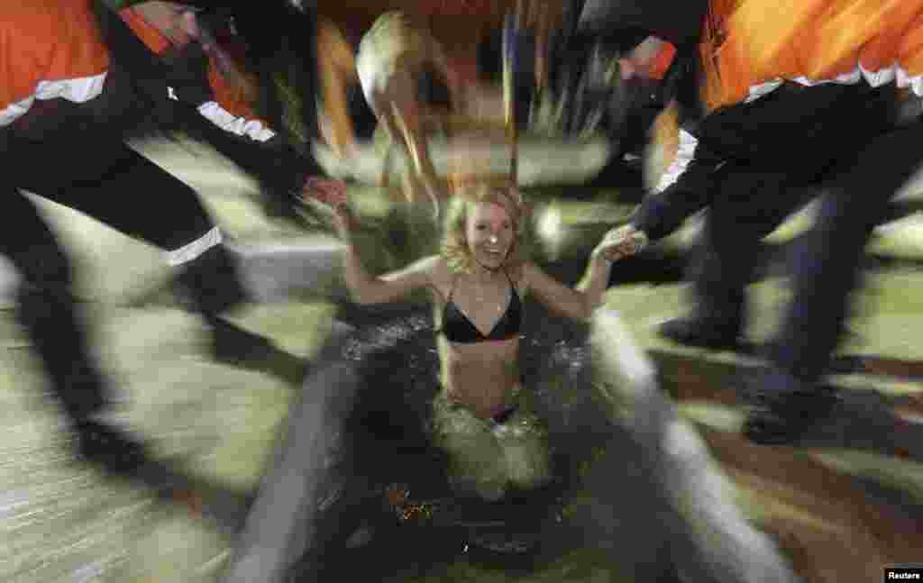 A woman is helped into the waters of the Bazaikha River after midnight, with temperatures about minus-20 degrees Celsius, in a surburb of Krasnoyarsk in Siberia. (Reuters/Ilya Naymushin)