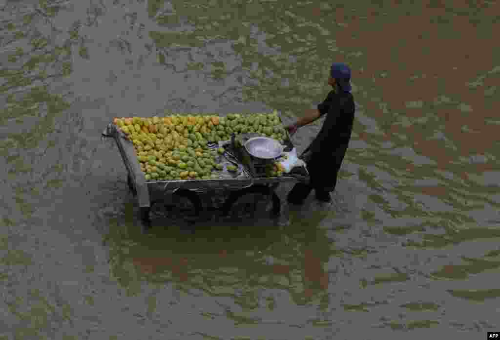 A Pakistani vendor pushes his cart through floodwater following heavy rain in Lahore. (AFP/Arif Ali)