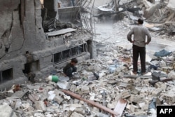 A Syrian boy collects items amid the rubble of destroyed buildings following reported air strikes in the rebel-held town of Douma, on the eastern outskirts of the capital, Damascus, on October 3.