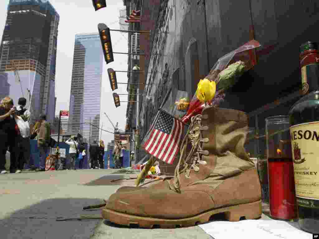 A pair of military boots, a bottle of whisky, and a memorial candle are placed at the base of a 9-11 memorial across the street from Ground Zero in New York, one day after bin Laden was killed. Photo by Kathy Willens for AP. 