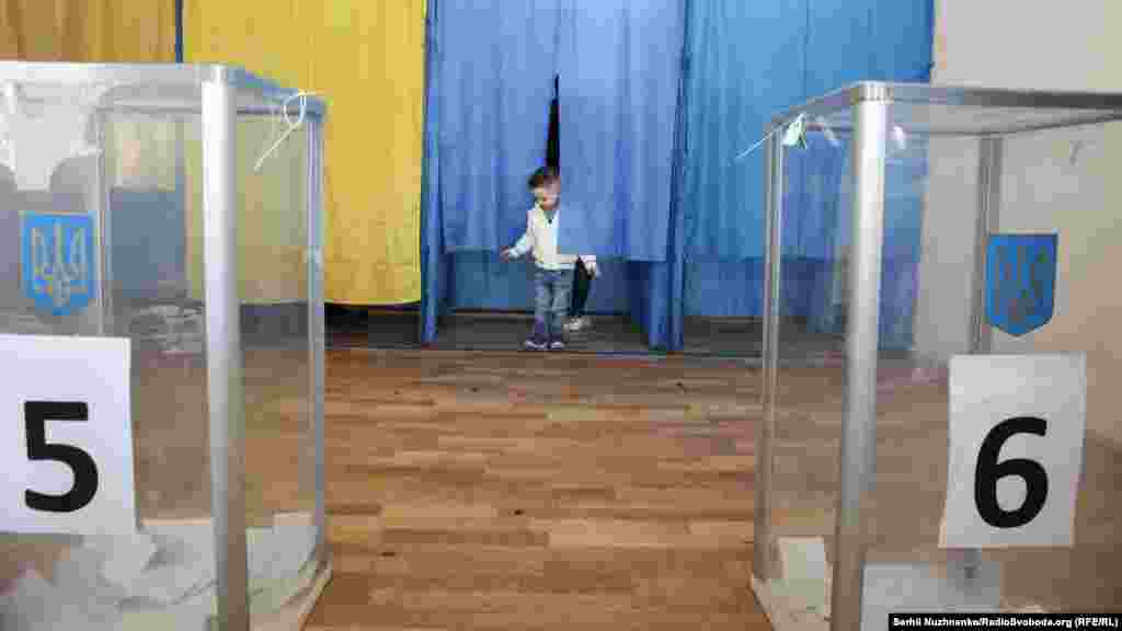 A child waits for his parents to cast their ballots at a polling station in Kyiv during the second round of Ukraine&#39;s presidential election on April 21.