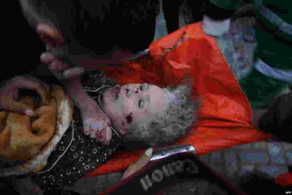 Palestinian paramedics carry an injured woman on a stretcher following an Israeli air raid on a house in Beit Lahia in the northern Gaza Strip. (AFP/Mohammed Abed)