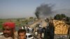 Passengers sit on the roof of a bus near oil tankers burning after "suspected militants" set fire to them on a highway near Shikarpur, in Pakistan's Sindh Province, on October 1. One day earlier, three Pakistani troops had been killed in a cross-border NATO air strike. <br /><br />Photo by Athar Hussain for Reuters