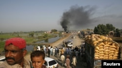 Passengers sit on the roof of a bus near burning oil tankers on a highway near Shikarpur, Pakistan, on October 1.