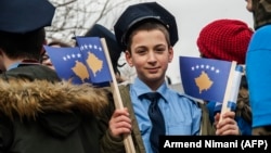 A young Kosovar boy dressed as a police officer holds Kosovar flags on the eve of the celebrations marking the 10th anniversary of Kosovo's independence, in Pristina on February 16.