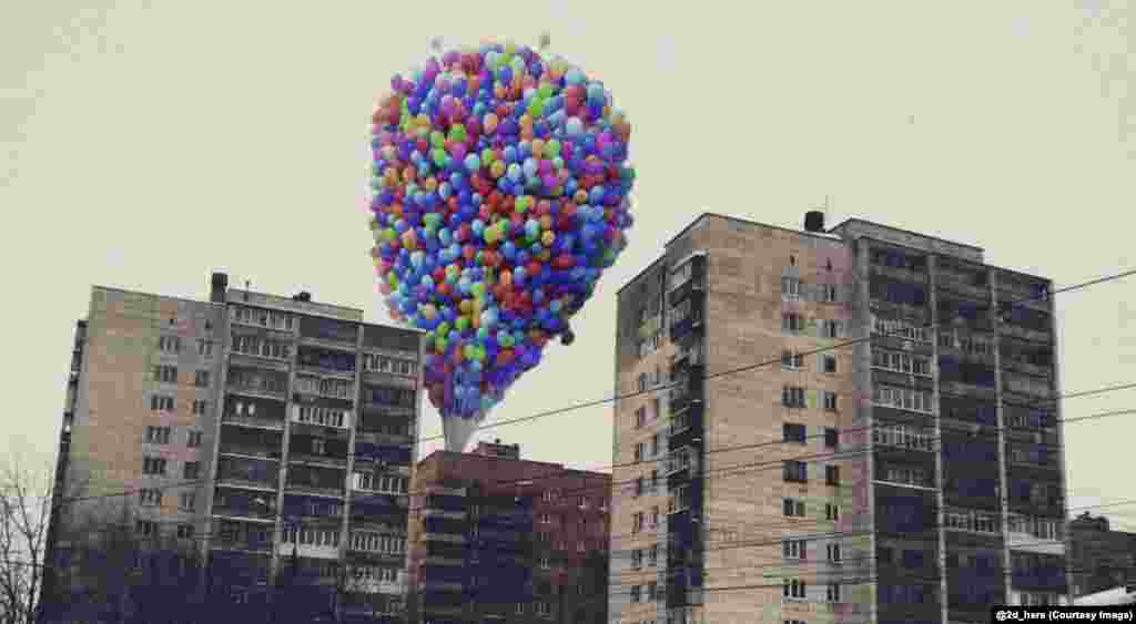 The balloons from the film Up, rising behind Soviet-era apartment blocks. Zubkov says that characters from an &quot;ideal, clean world contrast with dirty provincial streets.&quot;
