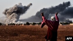 A woman reacts as smoke rises from the Syrian town of Kobani on October 13 after a strike from the U.S.-led coalition that is targeting the Islamic State militants besieging the town, seen from the Turkish-Syrian border.