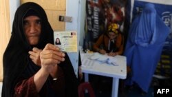 An elderly woman displays her identification card to vote in Afghanistan's forthcoming presidential election at a registration center in Herat. 