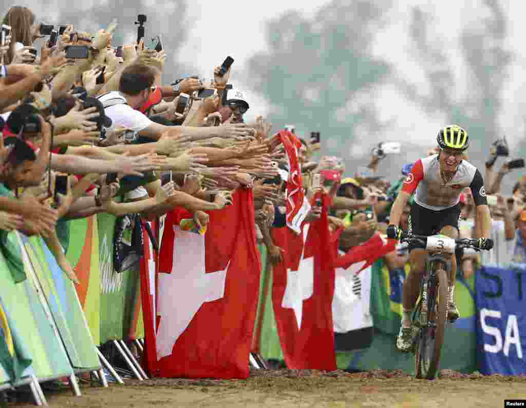 Nino Schurter of Switzerland celebrates his victory in men's cross-country cycling just before crossing the finish line.