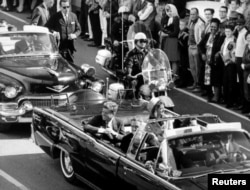 Кеннеди жубайы Жаклин менен машинада отурат. Кеннедиге ок жаңыларга бир нече мүнөт калганда тартылган сүрөт. АКШ, Даллас. 1963-жыл, 22-ноябрь.