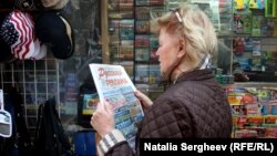 O femeie citește un ziar în rusă lângă un chioșc de la Brighton Beach, New York