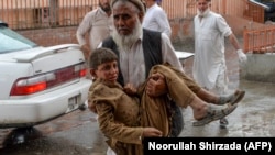 یک مرد در حال انتقال یک کودک به شفاخانه که در انفجار در مسجدی در ولسوالی هسکه مینۀ ننگرهار زخمی شده است.