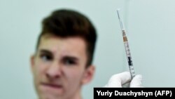 A nurse prepares to administer a measles vaccine shot to a boy in western Ukraine.