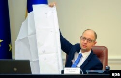 Premierul Arseni prezentând un document ce arată mecanismele corupției sub Ianukovici.