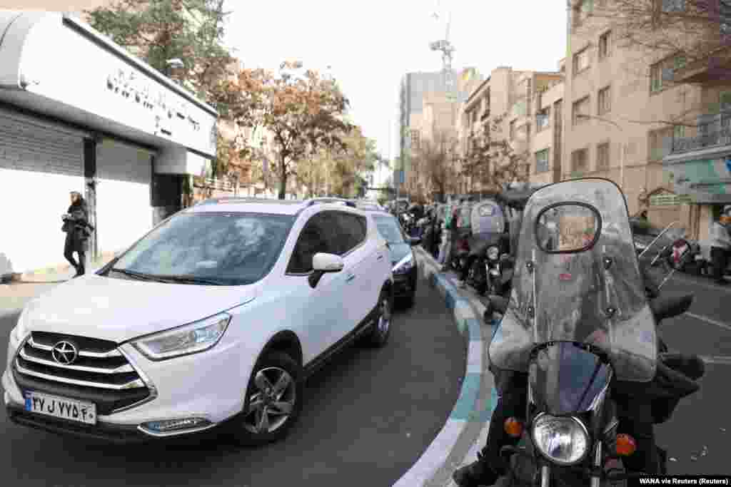 People wait for their turn outside a fuel station in Tehran.
