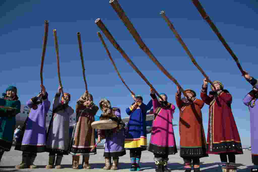 Musicians of the Nivkh indigenous ethnic group wear traditional costumes and raise Kalni musical pipes during a welcome ceremony for the Olympic flame at Yuzhno-Sakhalinsk airport on Russia&#39;s Pacific Island of Sakhalin. (AFP/Sochi 2014 Organizing Committee)