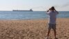 A man takes a picture as the Glory cargo ship carrying thousands of tons of grain makes its way from Odesa on August 7. 
