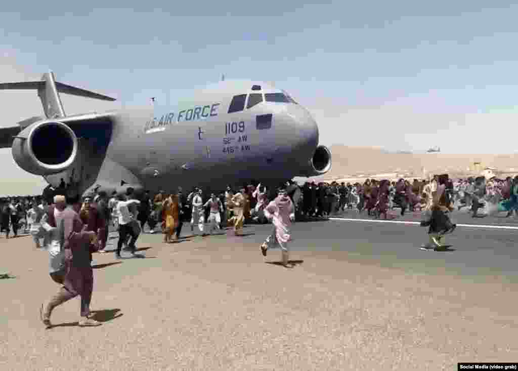 Desperate Afghans run onto the tarmac as a U.S. Air Force plane prepares to take off from Hamid Karzai airport on August 16.&nbsp; Some were seen clinging to the jet and then falling to their deaths.