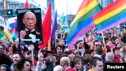 A demonstrator holds up a picture depicting Russian President Vladimir Putin with rainbow circles on his face, during a protest in Amsterdam on April 8.