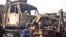 Pakistan -- A private security guard examines burnt trucks, destined for the NATO forces in Afghanistan, after an insurgents' attack at the Fasial terminal in Peshawar, 01Dec2008
