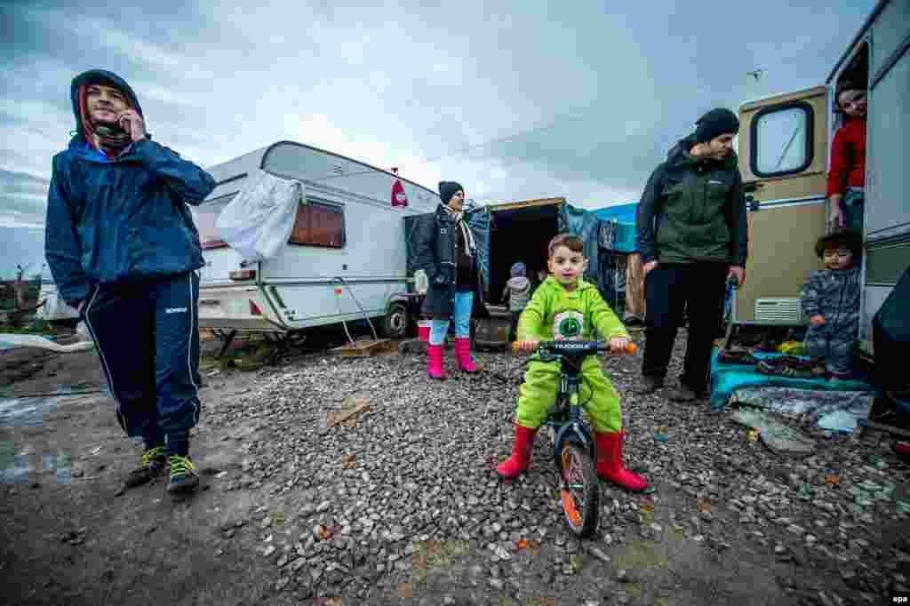 A refugee family stands in front of their caravan the day before Christmas in a camp nicknamed &#39;The Jungle&#39; in the French port of Calais. (epa/Stephanie Lecocq)