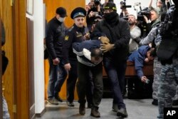 Российские силовики ведут одного из подозреваемых в нападении на «Крокус Сити Холл» Саидакрами Муродали Рачабализода в помещении Басманного суда Москвы, 24 марта 2024 года