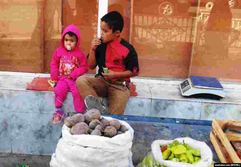Köçäniň gyrasynda söwda edip oturan çagalar