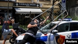 Disa protestues duke sulmuar një veturë policore në Tiranë më 2 korrik 2026. 