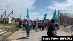 Люди после поминального обеда идут на кладбище за чертой села Талапкер.