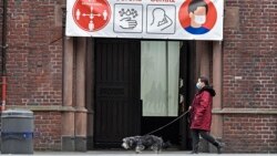 Женщина в маске выгуливает собаку на фоне надписи, призывающей соблюдать меры дистанцирования. Германия, 11 января 2021 года.